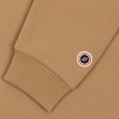 Gros plan sur le patch logo tricolore Sweet Pants au bas de la manche du sweat beige et finition bord-côte