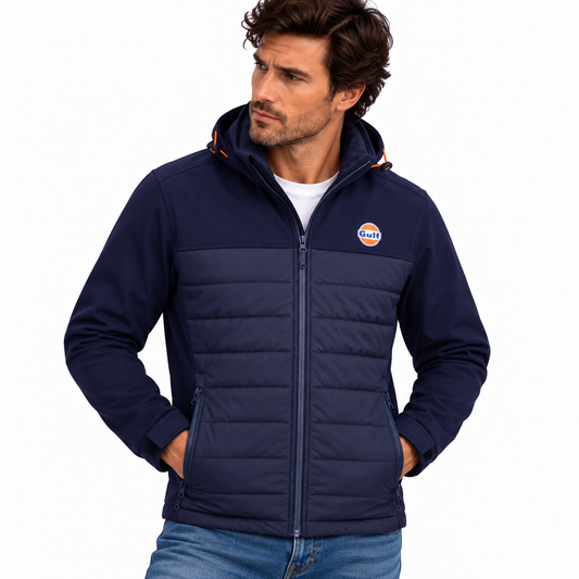 Homme portant une veste Gulf bleu marine à capuche, devant matelassé et manches softshell, avec un jean, sur fond blanc studio.